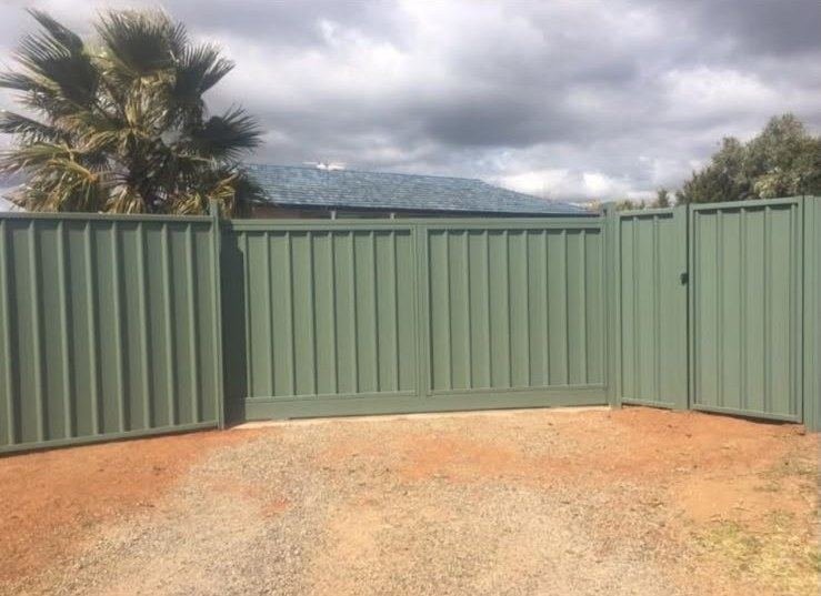 Green Colorbond fence and gate around a gravel yard