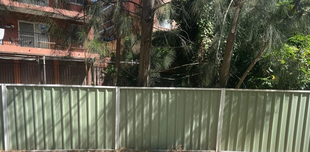 Repaired green Colorbond fence along a unit block