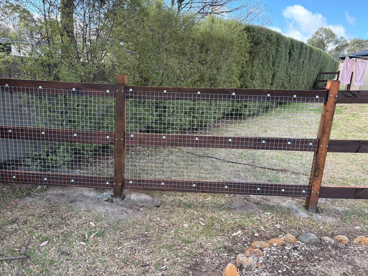 Hardwood post and rail fence with mesh along a garden
